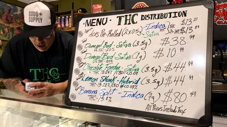 A sign listing cannabis names and prices. 