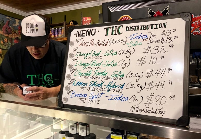 A sign listing cannabis names and prices. 