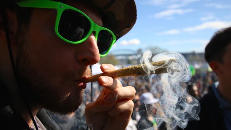 A man smokes an exaggerated joint at the park during a Vancouver 4/20 event.