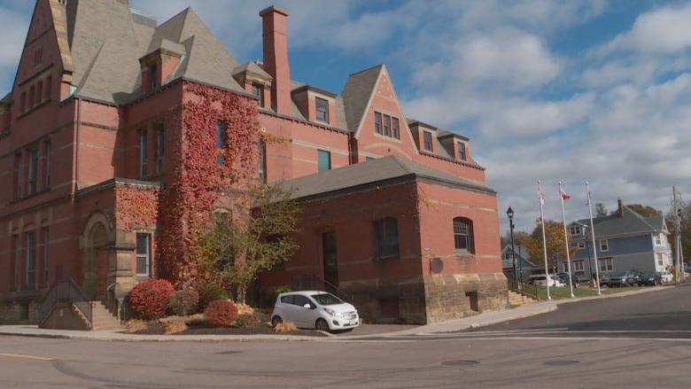 A red brick building with multiple floors and concrete steps photographed from the street.