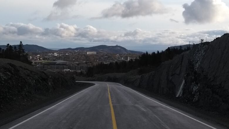 A road with a single yellow line in the middle. Rock walls rise on either side.