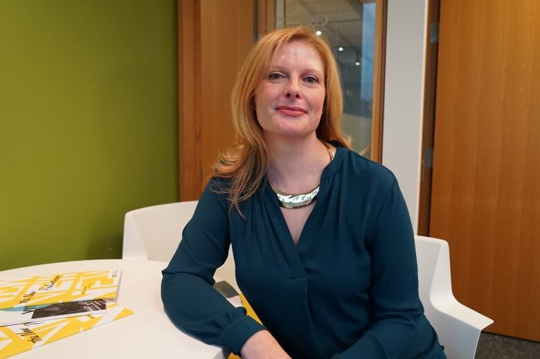 Sharon Avery sitting with her arm leaning on a table, looking at the camera. 