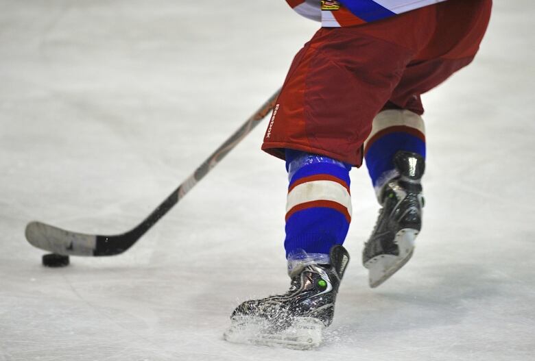 A hockey player wearing red and blue skating on an ice rink. 