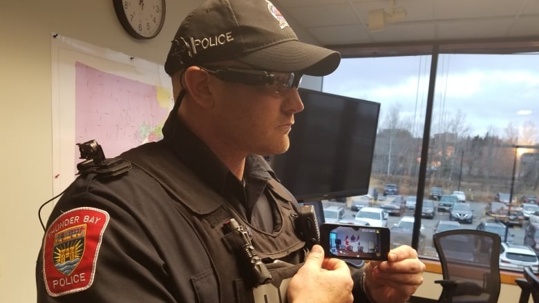 A side profile of a male police officer wearing sunglasses and a ball cap