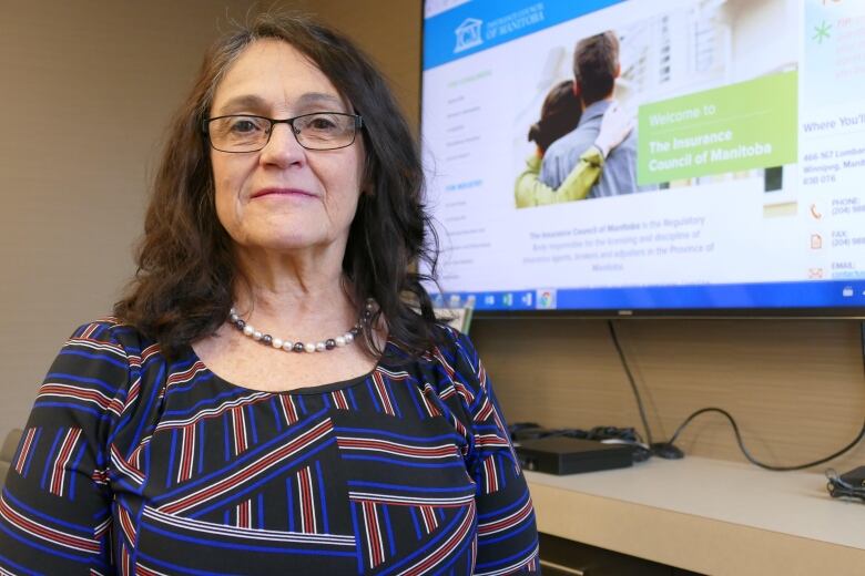 A woman stands in front of a screen.