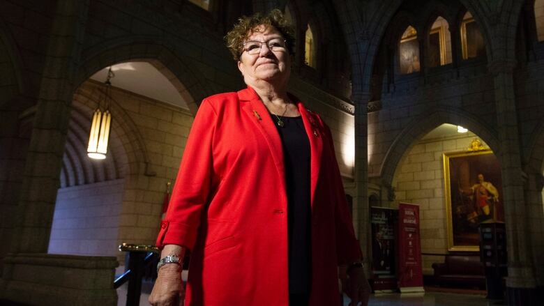 Senator Yvonne Boyer poses for a photo in the foyer of the Senate on Parliament Hill in Ottawa. She wears a red blazer and a black shirt. 