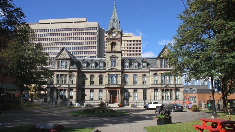 City hall with its clock tower and three-story facade stands over grassy areas of a large square