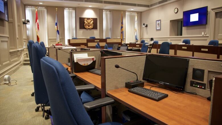 The council chambers at Halifax City Hall show blue swivel chairs sitting at various desks that circle the walls.