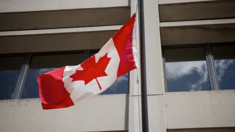 A Canada flag in front of a building.