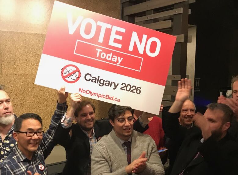 A group of people holding a sign that reads ' Vote No Today Calgary 2026' look happy.