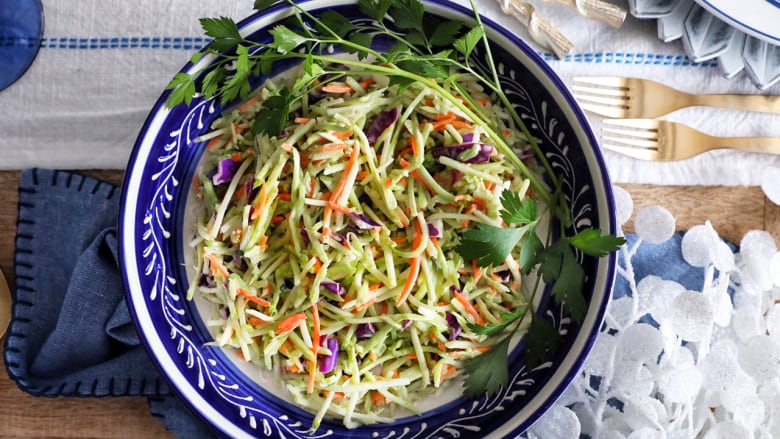 Overhead shot of a blue bowl of broccoli walnut slaw on a table with blue and white decor.