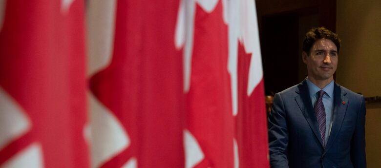 Trudeau stands next to a Canadian flag