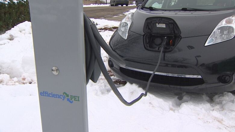 An electric vehicle being charged at an Efficiency P.E.I. charger, with snow on the ground.