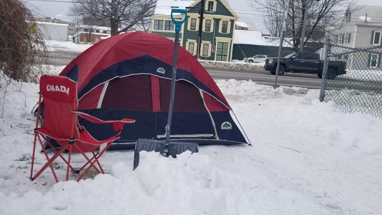 A red tent and red lawn chair sitting in a pile of snow