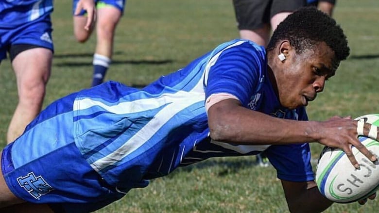 A man holds a rugby ball.