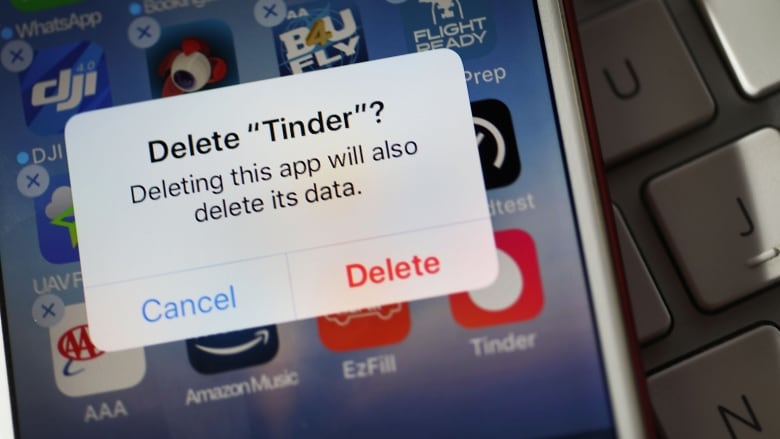 A close up shot of a phone screen, with a notification asking if the user wants to delete the app Tinder