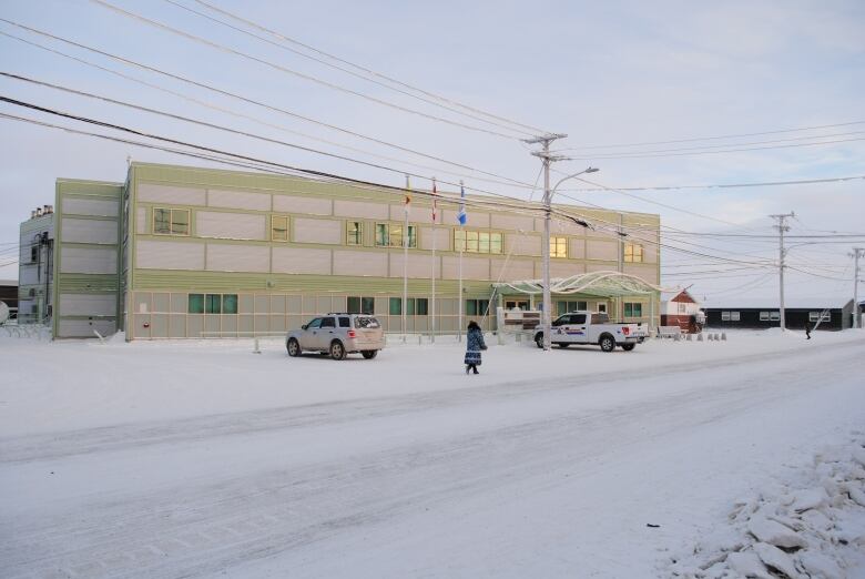 A snow covered ground before a modern looking building. 