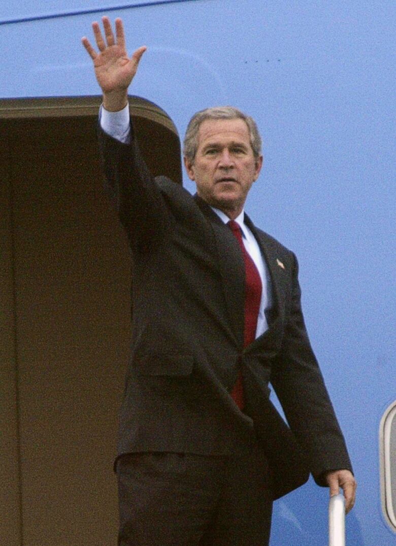 Man waves while on top of stairs to board plane