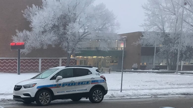 Two police cars sit outside a school building.