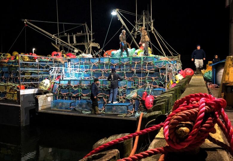 boats and lobster traps tied up in a dock in the dark.