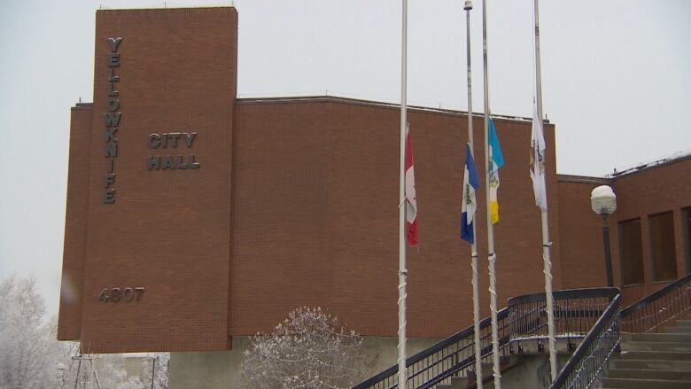 A brick building with flags in front in a snowy setting.