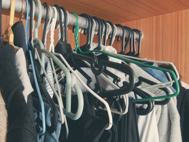 A messy closet full of hanging clothes. 