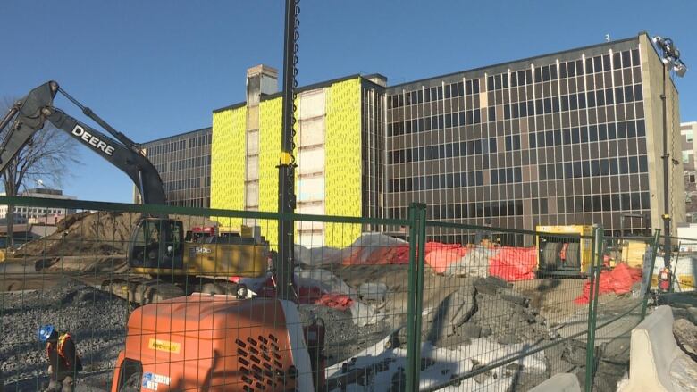 A construction site with heavy machinery behind a fence. 