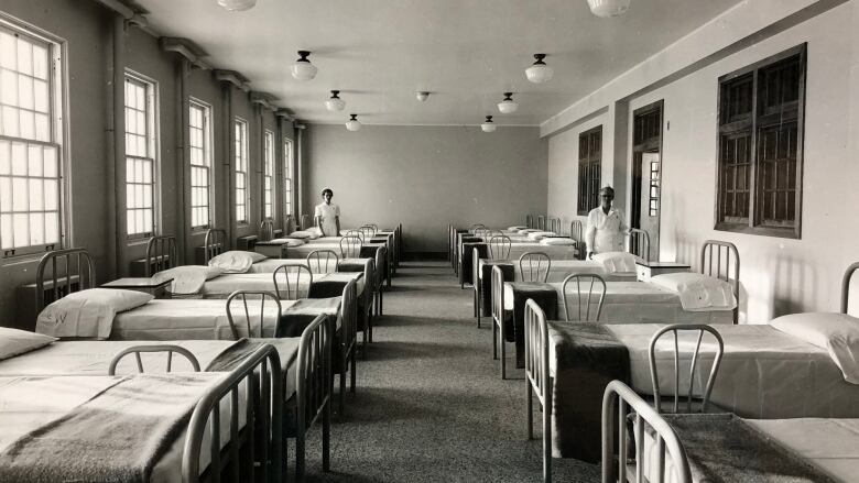 Black-and-white photo of beds in a dormitory.