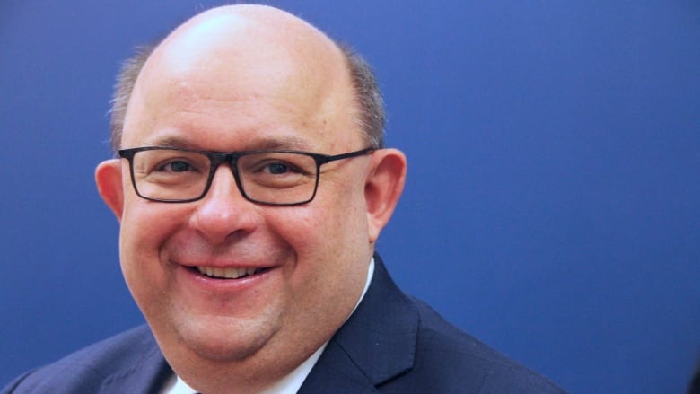 Portrait of a man wearing glasses and a suit.