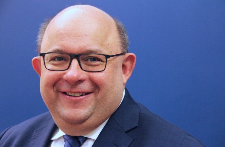 Portrait of a man wearing glasses and a suit.