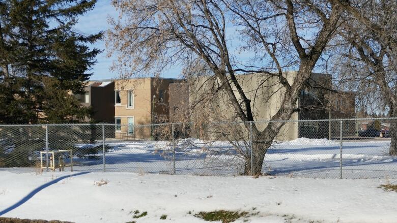 A building sits in grounds behind a chain-link fence.