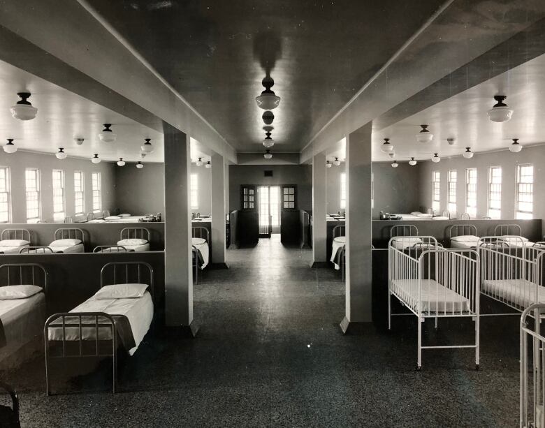 Black-and-white photo of beds in a dormitory.