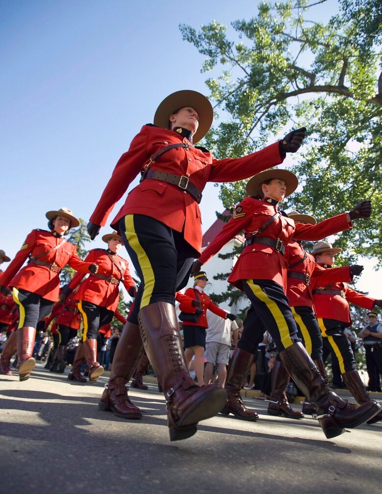 Rows of RCMP officers march while wearing their Red Serge uniforms. 