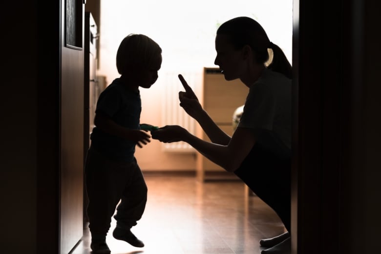 Parent toddler child discipline with woman wagging a finger at child.