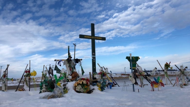 A memorial featuring jerseys, hockey sticks and a cross with the message 