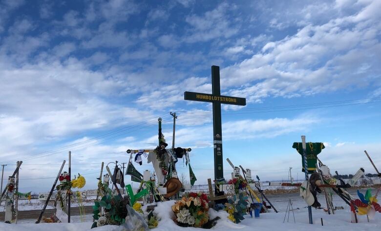 A memorial featuring jerseys, hockey sticks and a cross with the message 