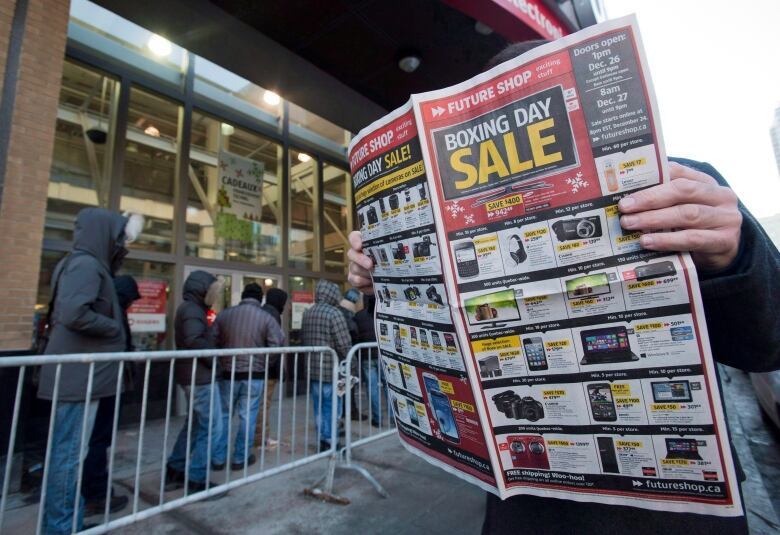 A man looks at a flyer offering discounts outside an electronics store on Boxing Day.