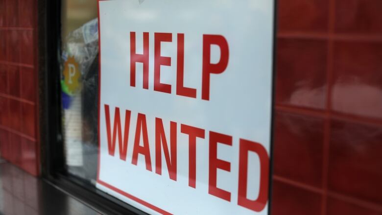 A help wanted sign hangs in a window