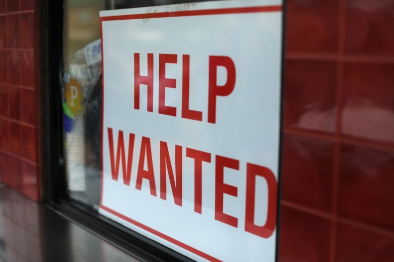 A help wanted sign hangs in a window