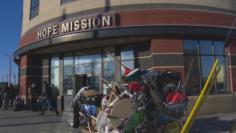 Shopping cart piled high with belongings and clients outside Hope Mission.