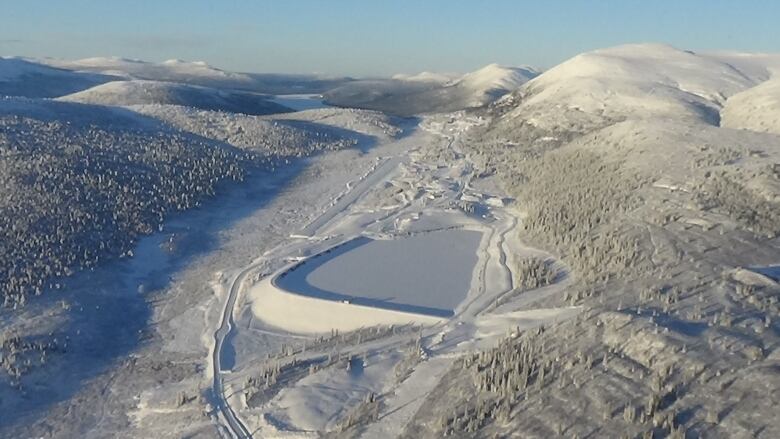 A mine site surrounded by hills, seen in winter.