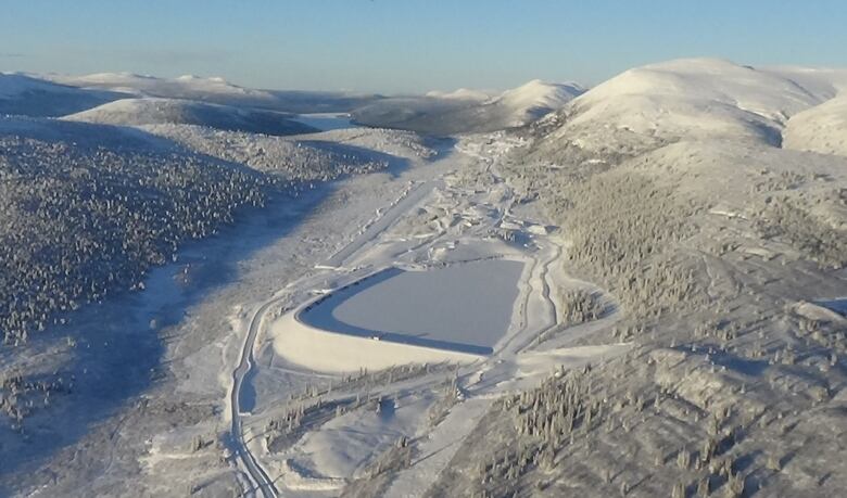 A mine site surrounded by hills, seen in winter.