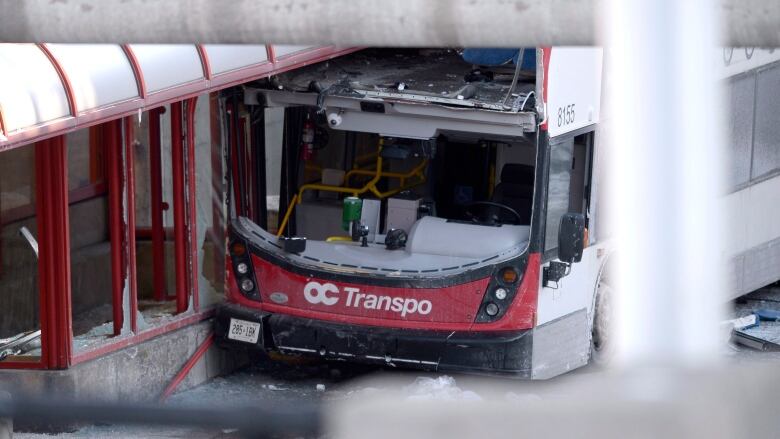 An empty red-and-white bus with a broken windshield