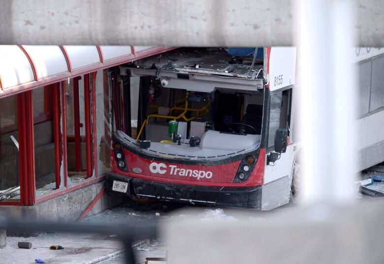 An empty red-and-white bus with a broken windshield