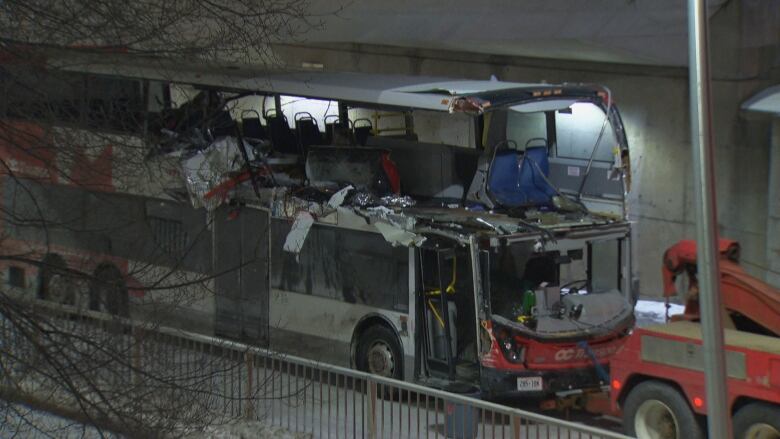 A tow truck attached to a damaged OC Transpo double decker bus. 