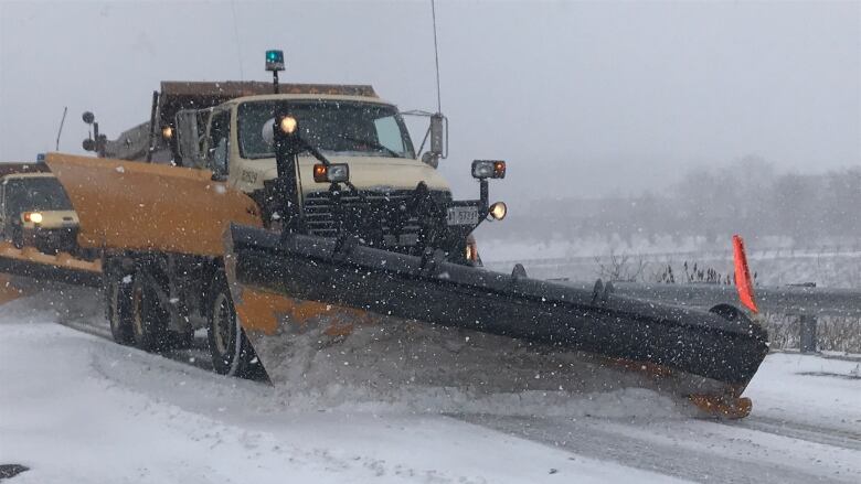 A plow clears snow on a highway road. 