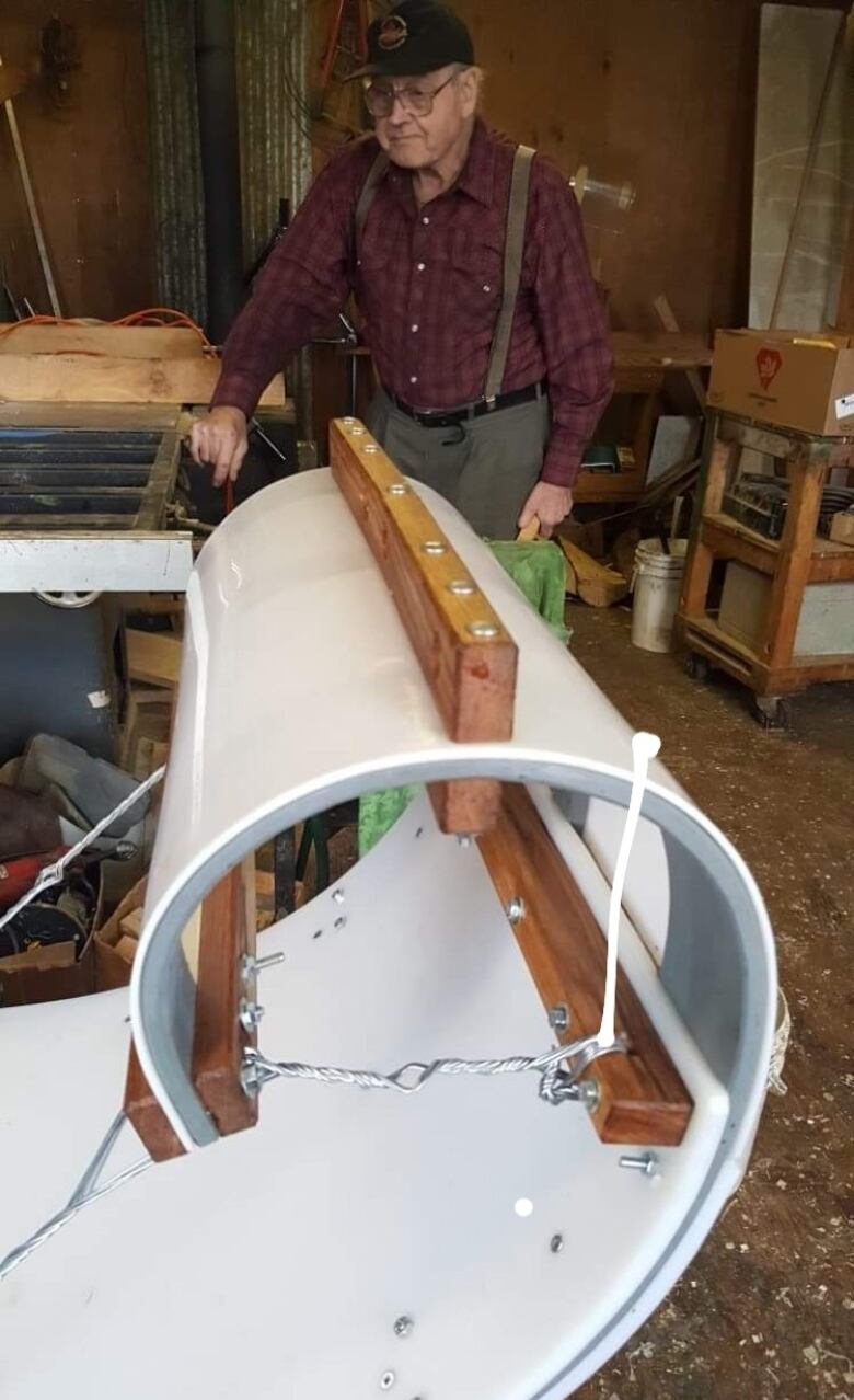 A man stands behind a toboggan.