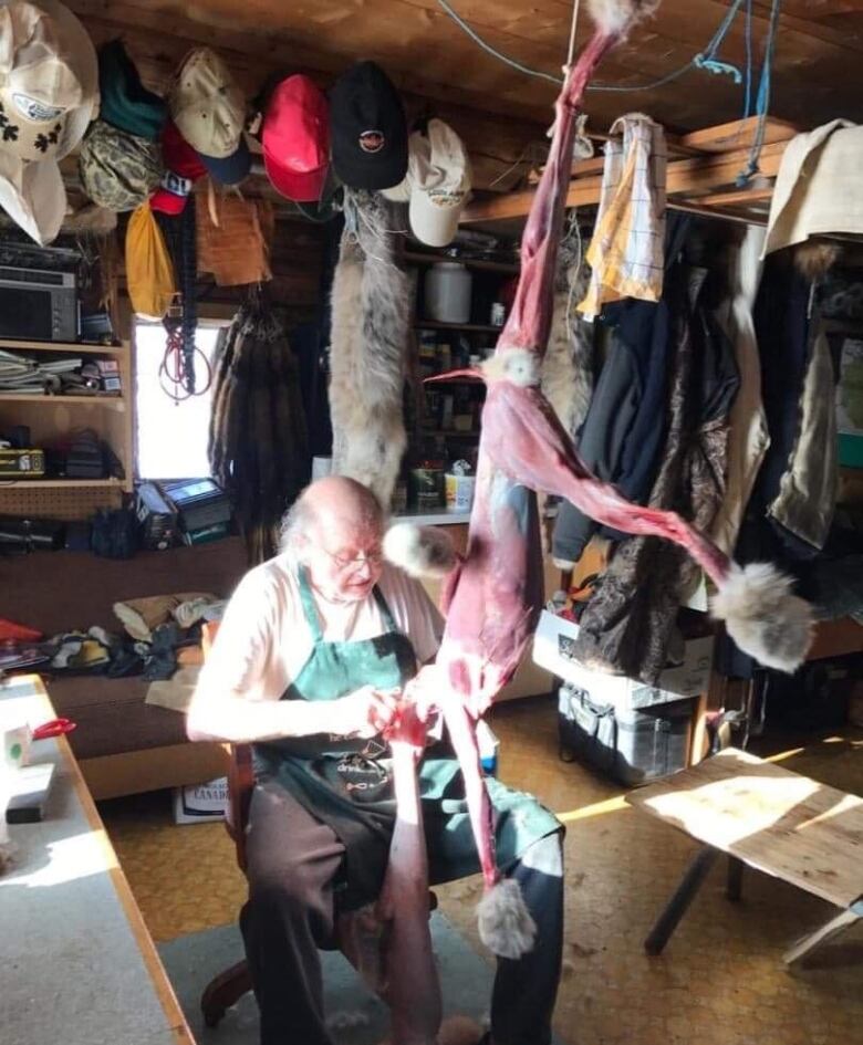 A man skins an animal in a cabin.