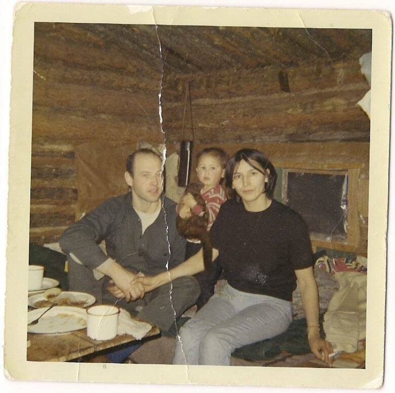 An old photo of a family sitting by a table.