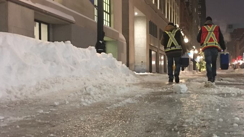 Two people walk on an icy pedestrian street.